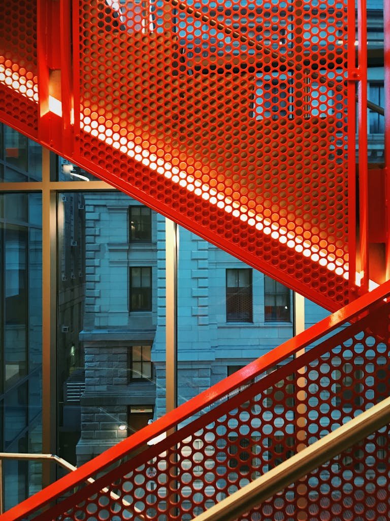 Vibrant red metal stairs with urban Boston architecture background.